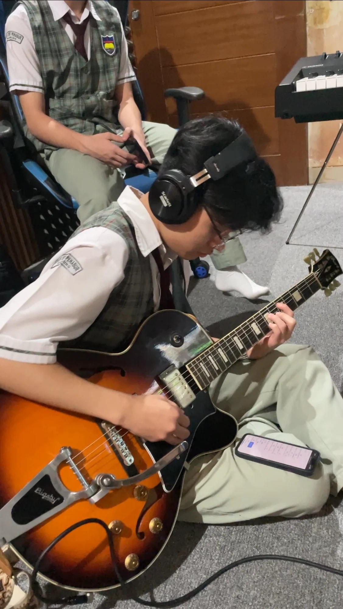 Student playing guitar as Keane guides the session